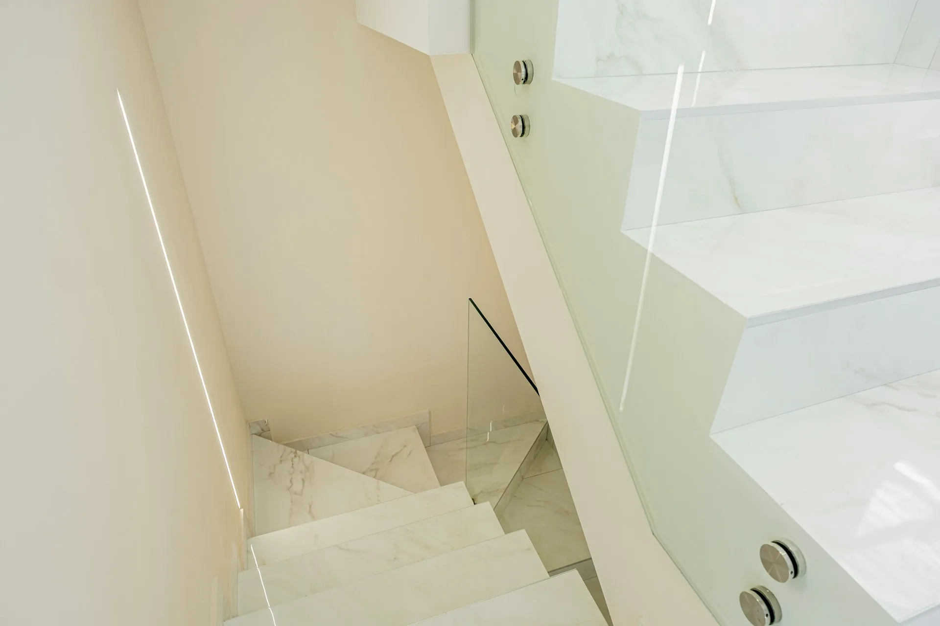 Stairs with white steps and glass railings.