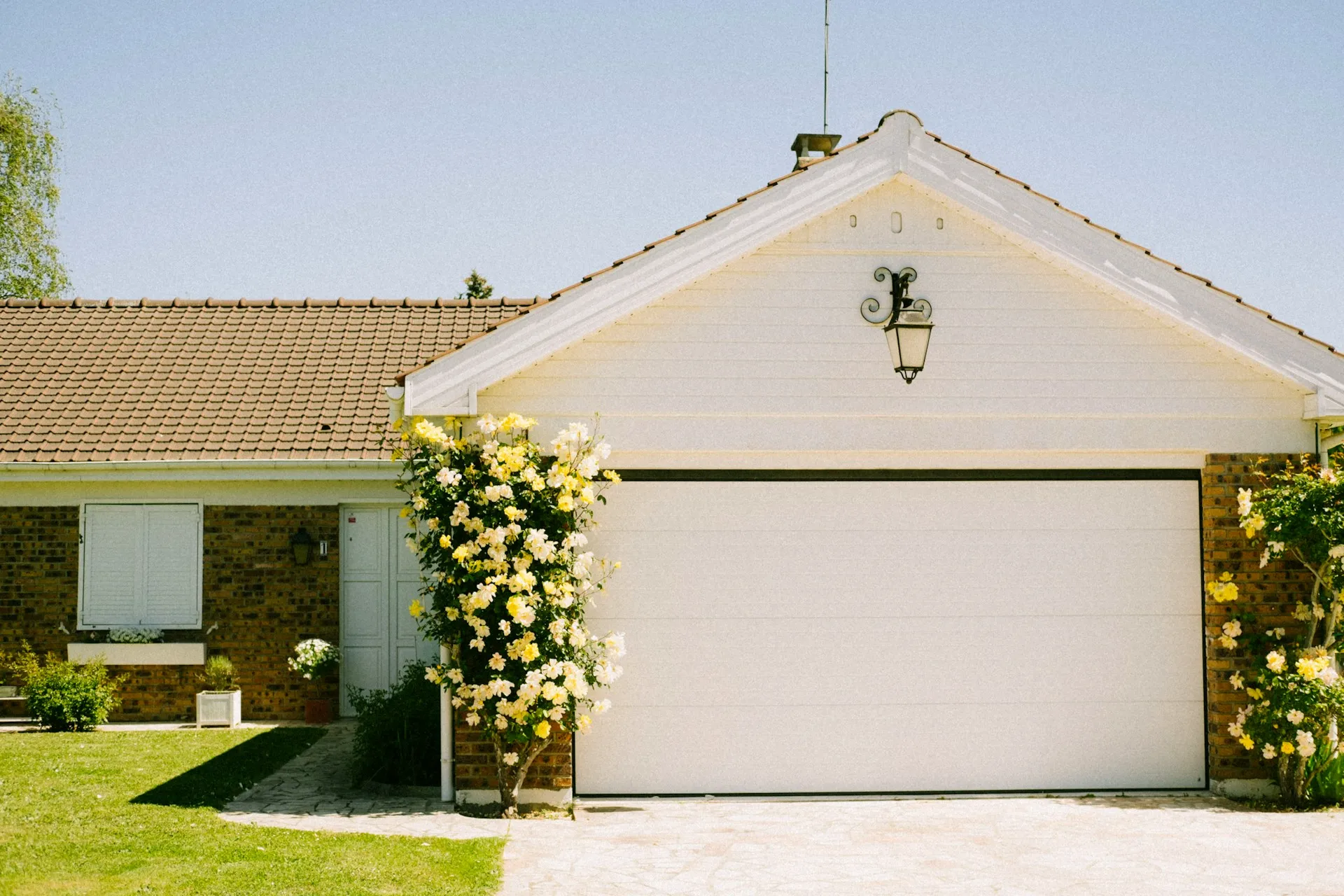 House California real estate with a white garage door and yellow flowers on the wall.