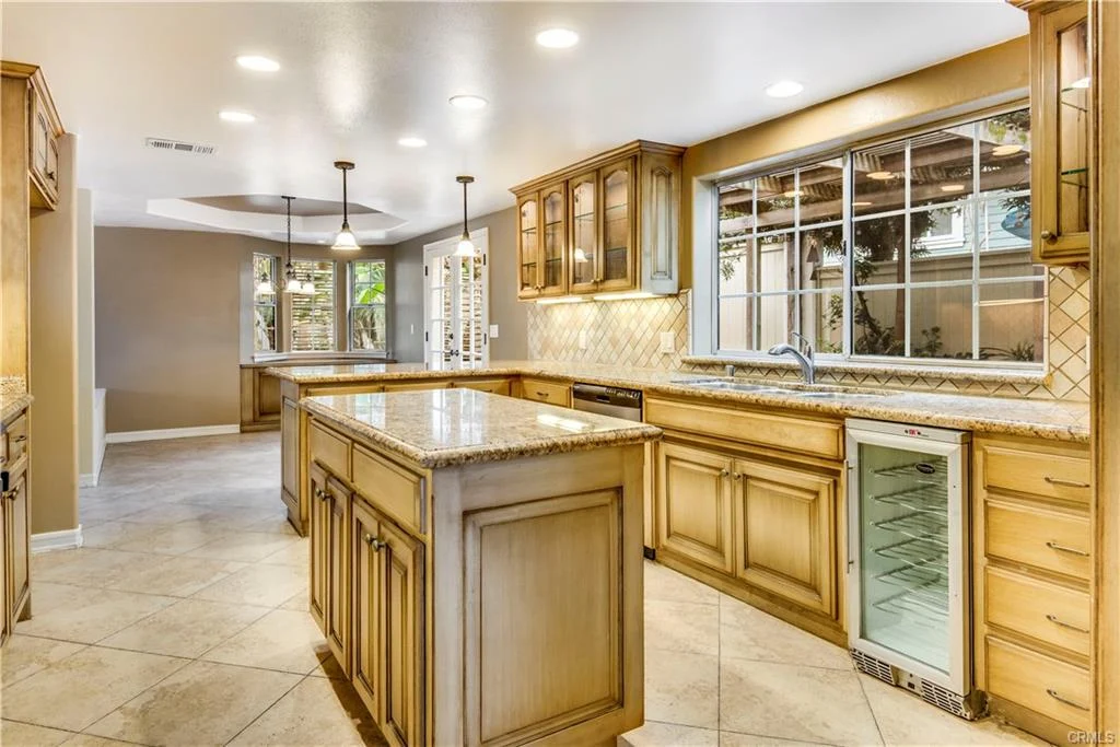 kitchen with wood cabinets, island, granite counter, appliances, tile floor, and windows