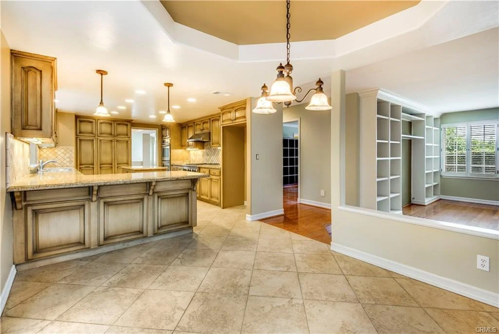 kitchen with wood cabinets, granite counter, open to living area with shelves