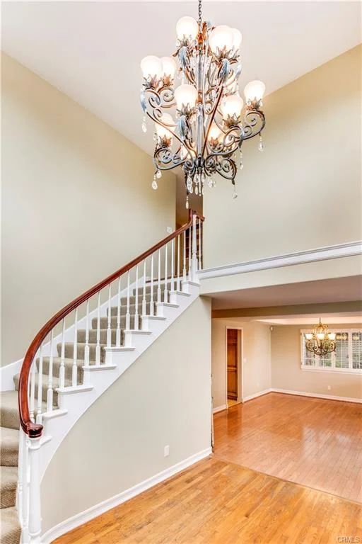 Staircase with wooden handrail, chandelier, and hardwood floor