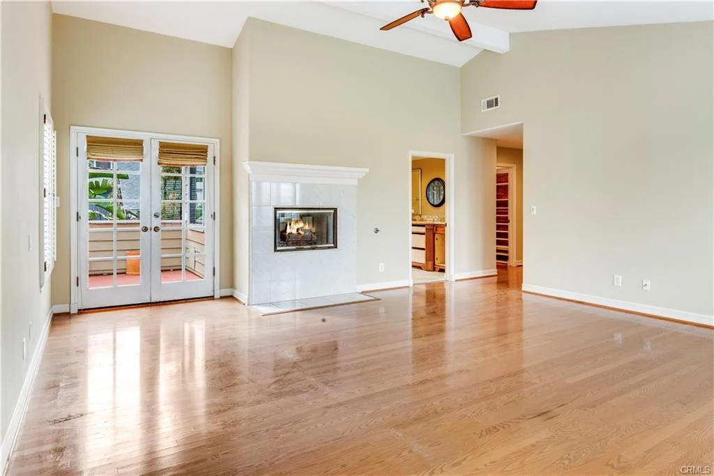 living room with wooden floor, fireplace, big windows, ceiling fan, and doors to patio