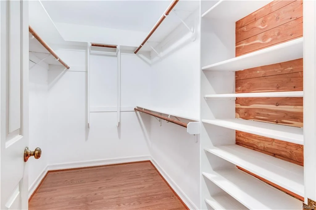 Closet with white walls, wooden shelves, and hardwood floor