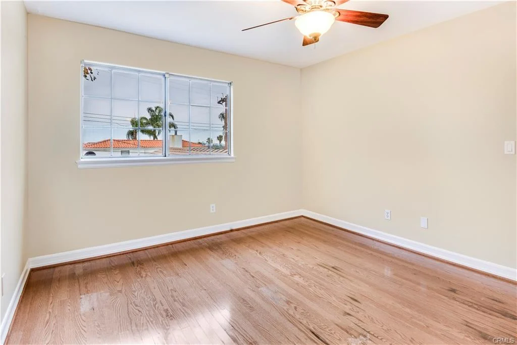 Empty room with ceiling fan, hardwood floor, big window, and light walls