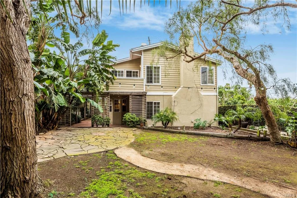 Two-story house California real estate with green plants and stone path leading to it