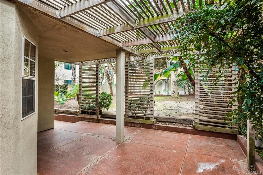 Patio with concrete floor, green plants, and wooden lattice near a house California real estate
