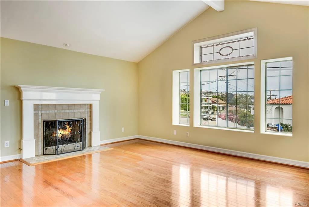 Large room with wood floors, big windows, and shutters.