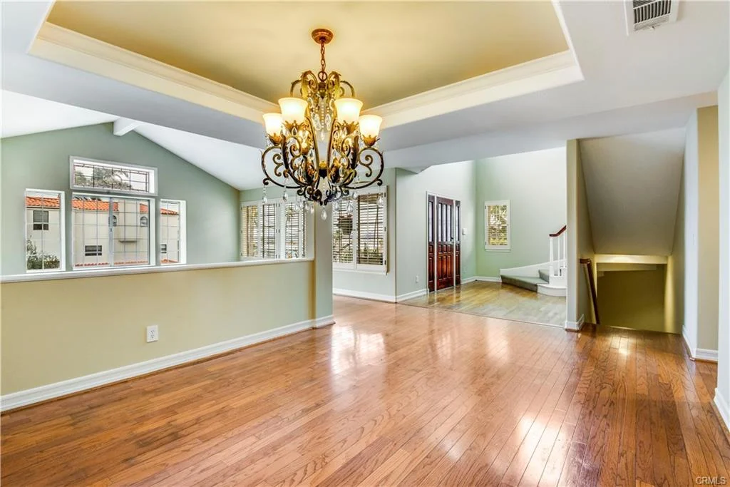 Hallway with wood floors, a staircase, and a chandelier.