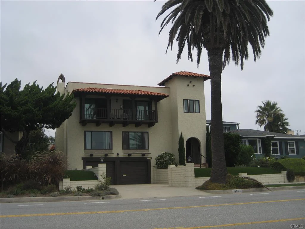 House in California real estate with flat roof, balconies, palm trees, and yard