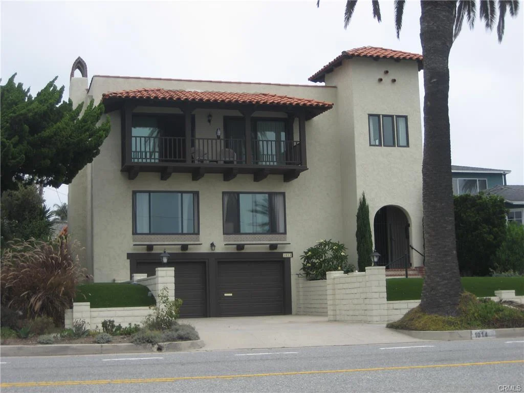House in California real estate with tile roof, balcony, driveway, garage, palm trees, and plant