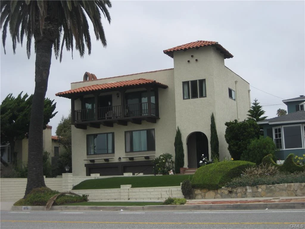 House in California real estate with tile roof, balcony, yard, and palm trees