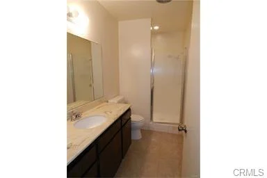 Bathroom with sink vanity, toilet, and shower area.