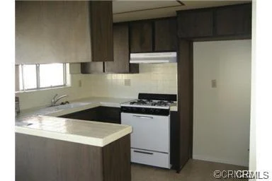 Kitchen with dark wood cabinets, white stove, and simple counter.