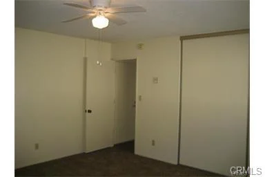 Room with ceiling fan, light walls, and closet door.
