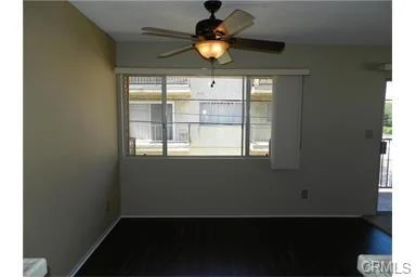 Room with ceiling fan, large window, and wood floor.