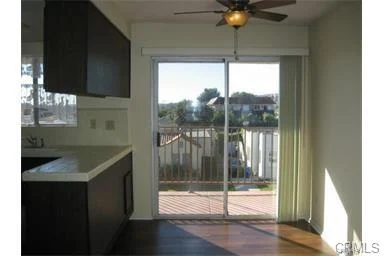 Kitchen with dark cabinets, ceiling fan, and sliding glass doors to outdoor deck.