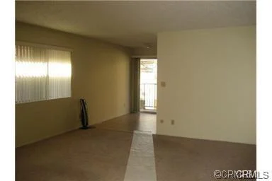 Room with beige walls, carpet floor, window, doorway