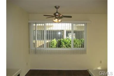 Room with ceiling fan, large window with blinds, and light walls.