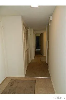 Corridor with light walls, carpet floor, and doors on both sides.