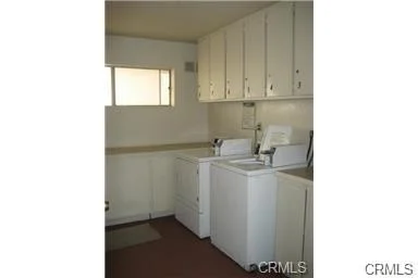 Laundry room with white cabinets, washing machine, dryer, and window.
