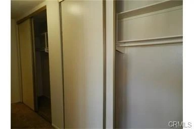 Narrow hallway with sliding closet doors and open space with white shelf.