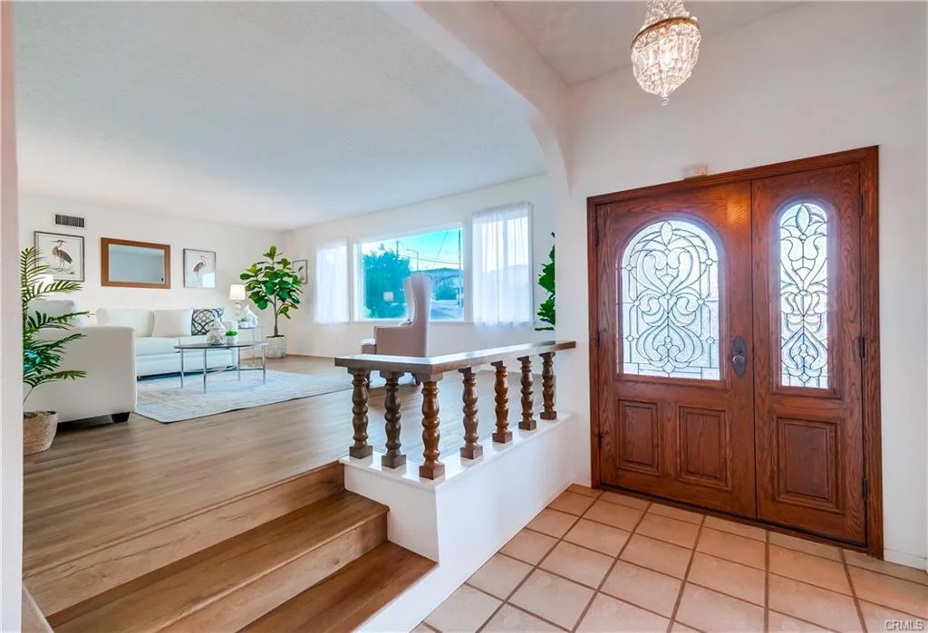 Home entrance with wooden door, stairs, white walls, windows, and furniture