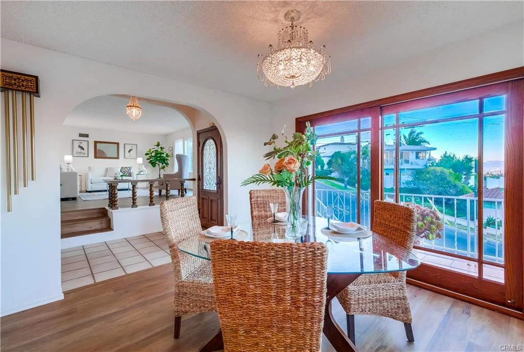 Dining area with glass table, chairs, flowers, and window