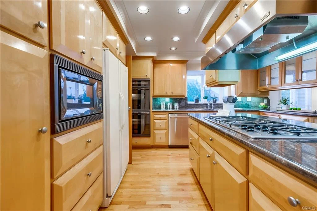 Kitchen with wooden cabinets, stainless steel appliances, gas stove, and granite island.