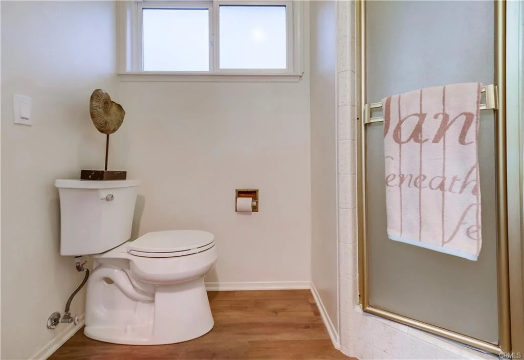 Bathroom with toilet, shower, and towel on wall.