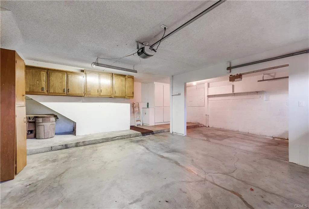 Garage with concrete floor, open space, cabinets, door, and ceiling lights