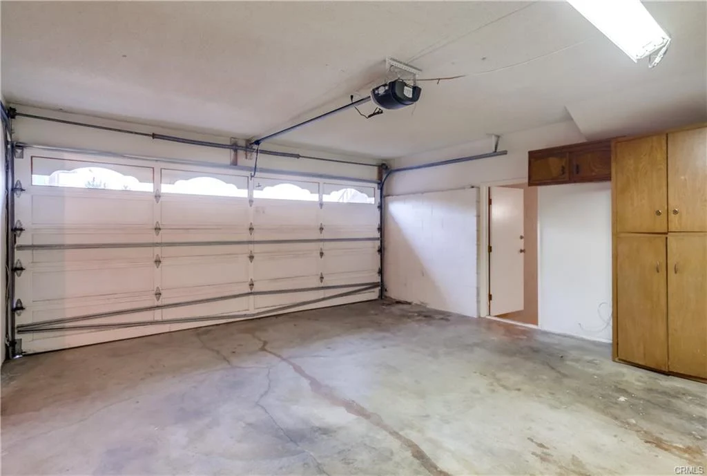 Garage with large door, concrete floor, and storage area