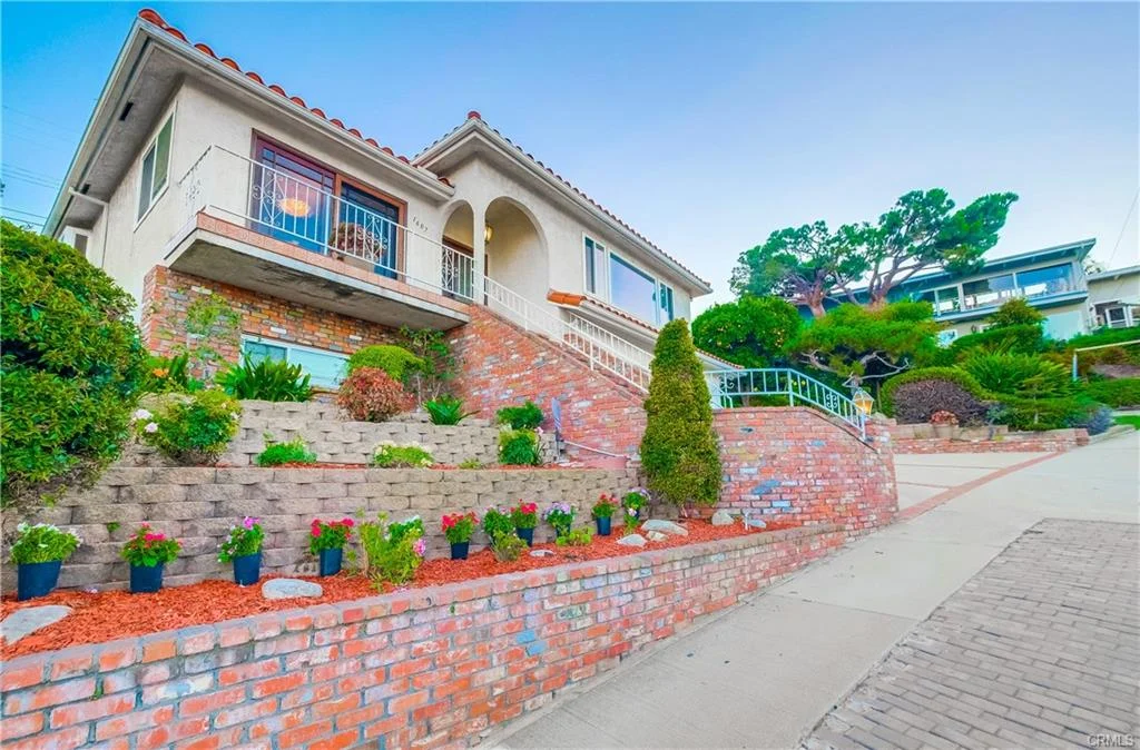 House in California real estate with brick exterior, driveway, flowers, and greenery