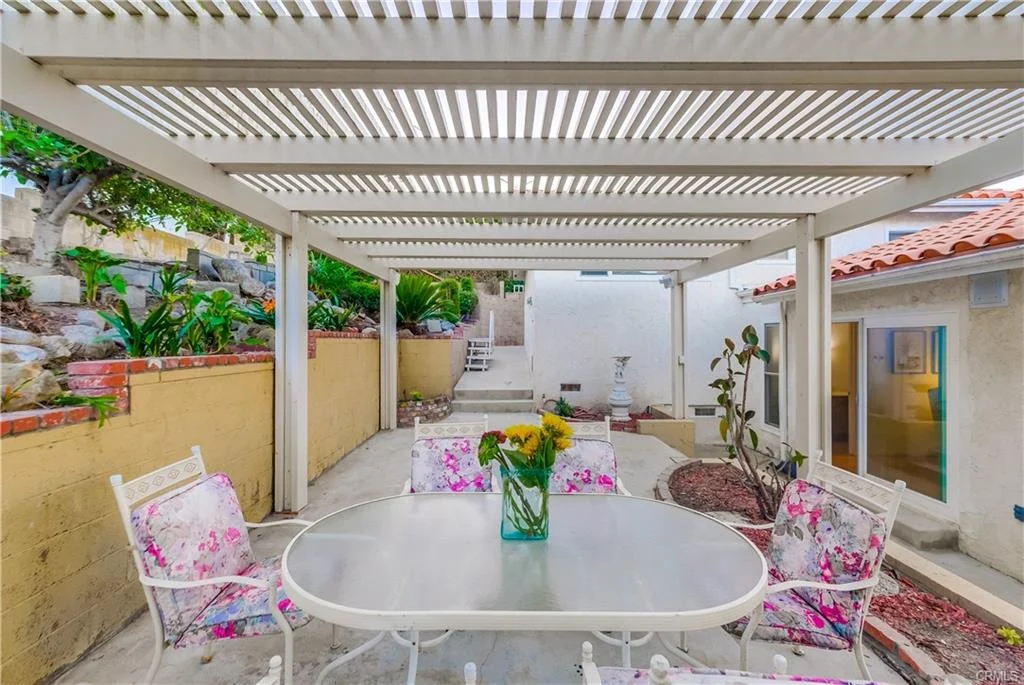 Patio with table, chairs, pergola, plants, and wall