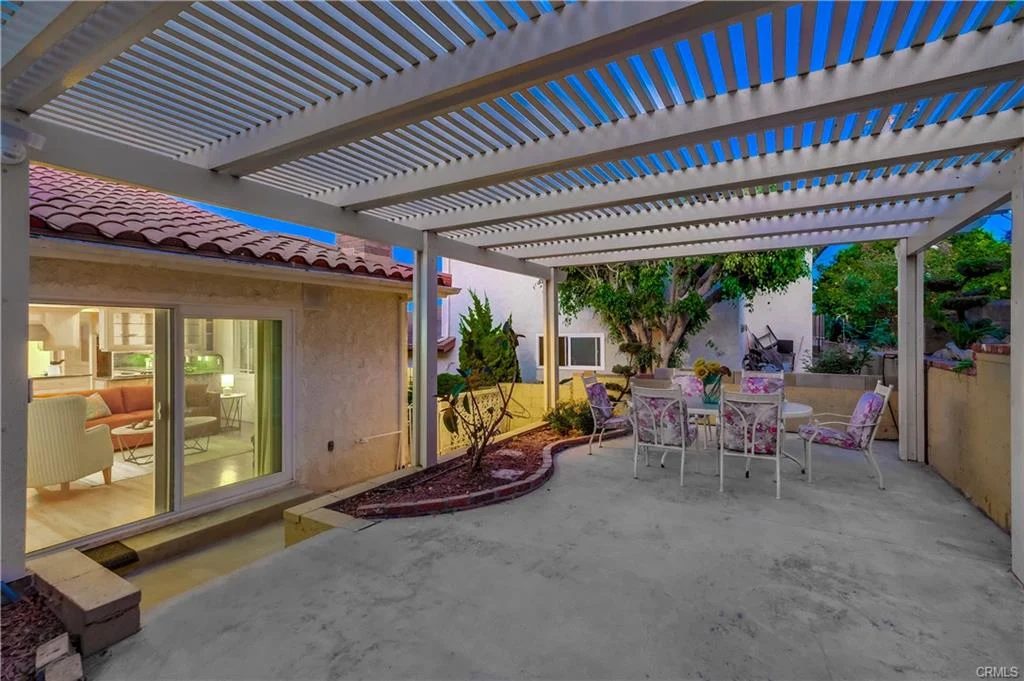 Covered patio with seating, greenery, and exterior of house in California real estate