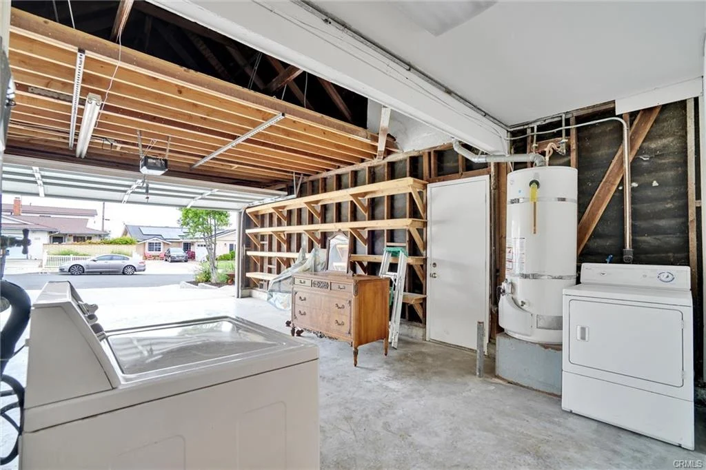 Garage with wooden shelves, washer and dryer, dresser, and door.