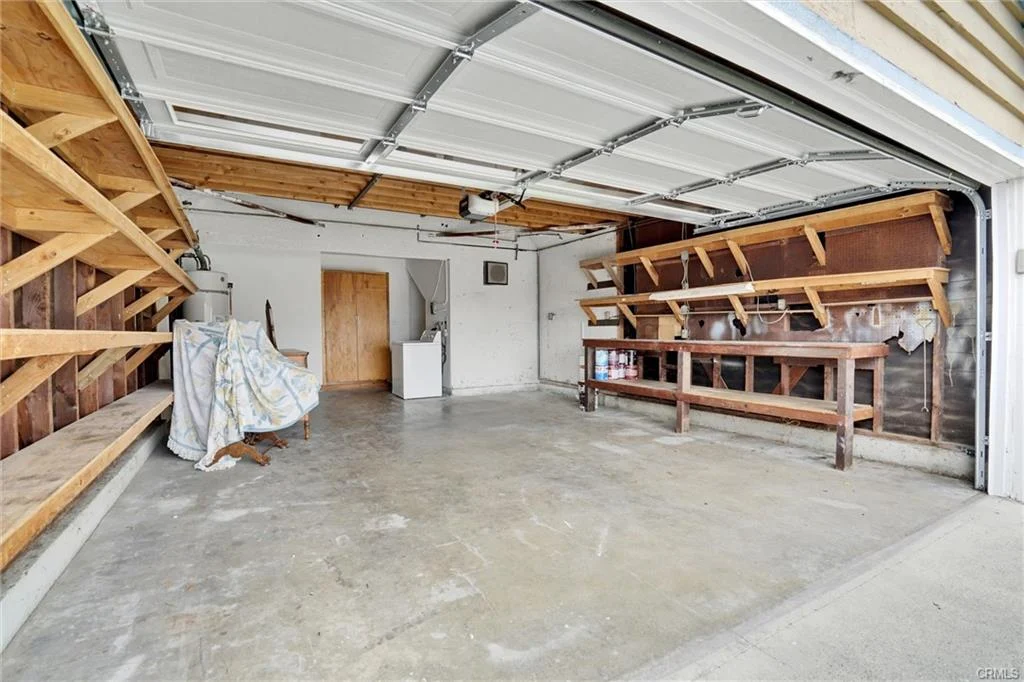 Garage with wooden shelves, workbench, concrete floor, and closed door.