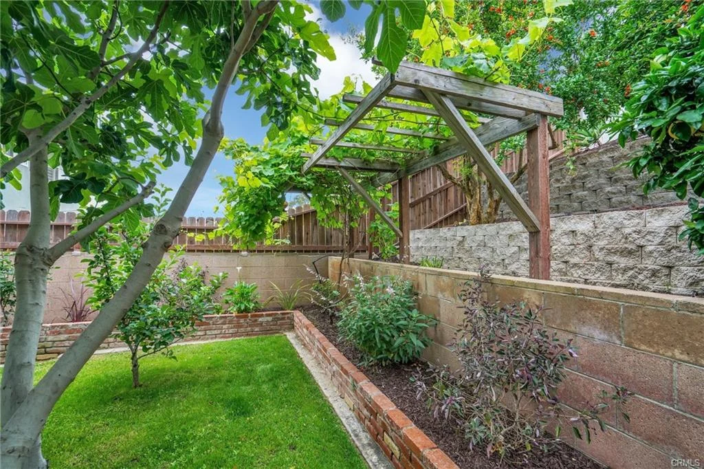 Garden with green plants, gazebo, and stone walls.