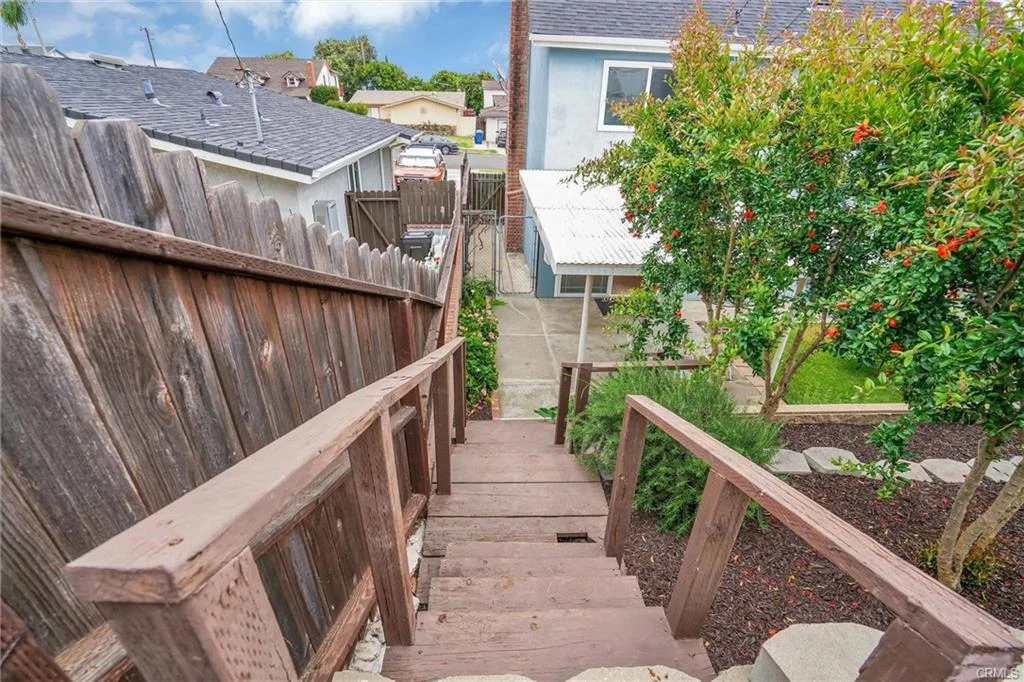 California real estate house with wooden staircase, garden, and house beyond.