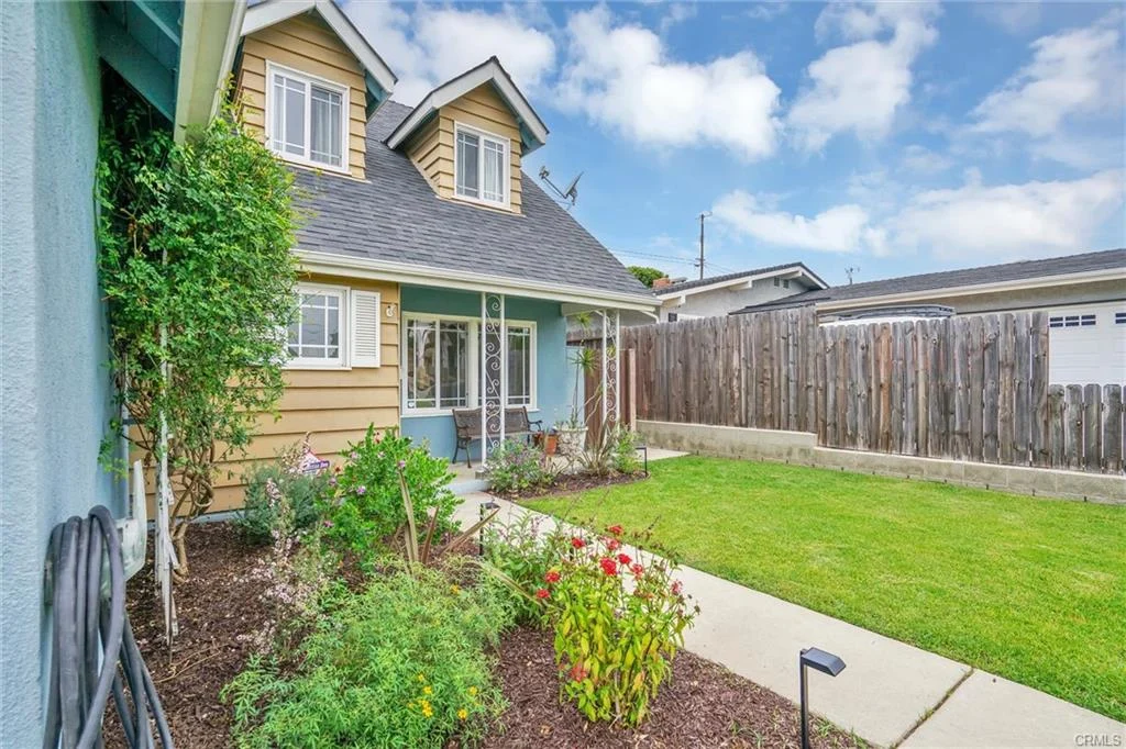 California real estate house with yellow and blue siding, garage, lawn, garden, and front porch.
