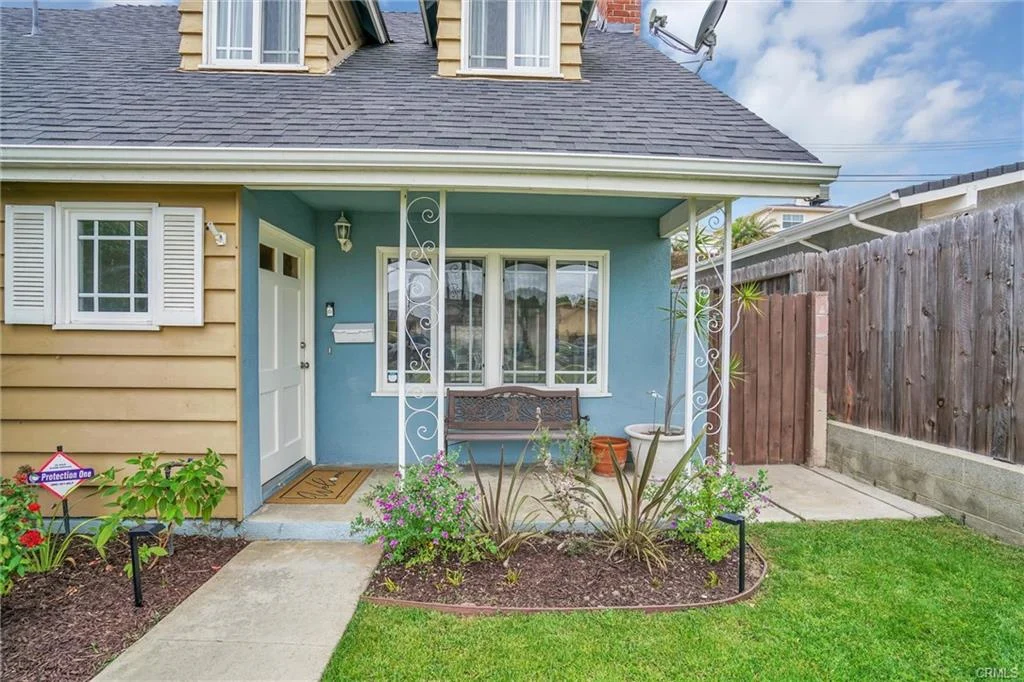 California real estate house with blue front wall, porch bench, and garden plants.