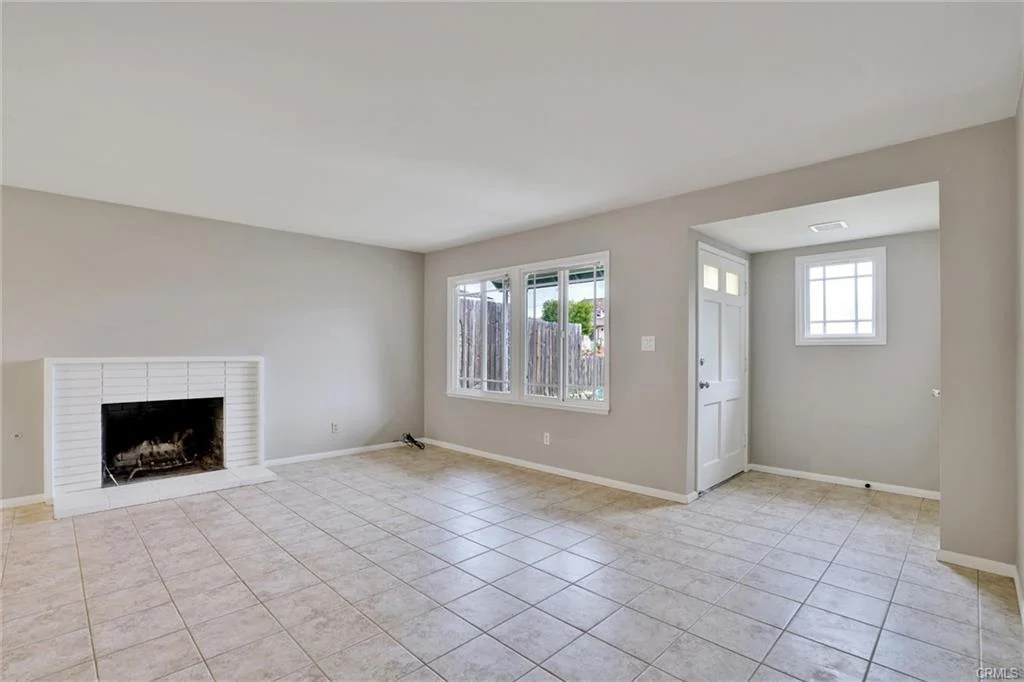 Living room with tile floor, fireplace, and door leading outside.