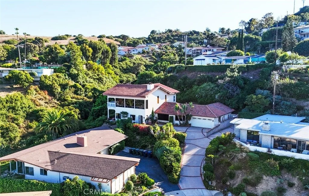 House California real estate with brown roof and driveway, trees, and nearby houses in neighborhood aerial view