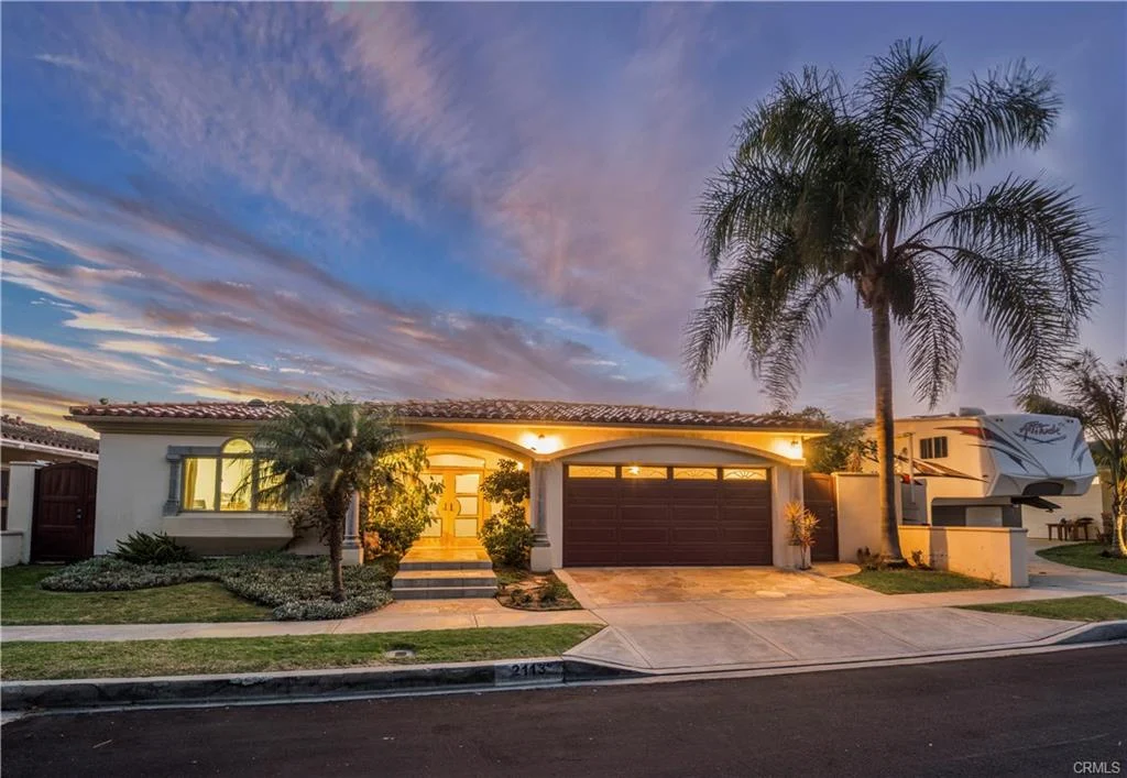 Suburban house with garage, palm trees, and landscaping, California real estate.