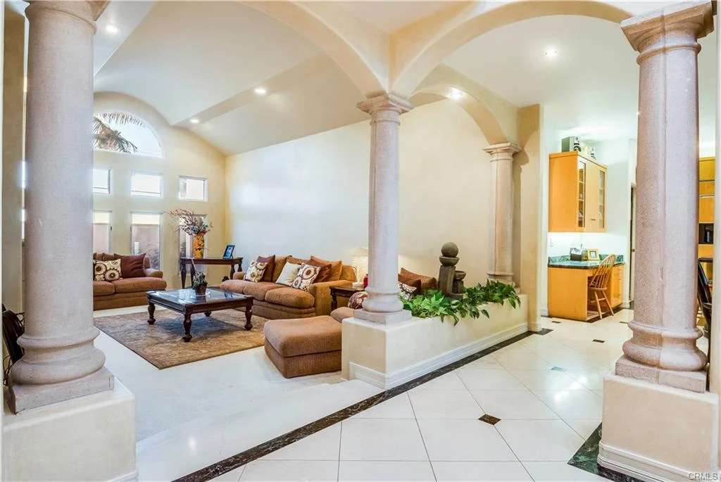 Living area with sofas, coffee table, and columns.