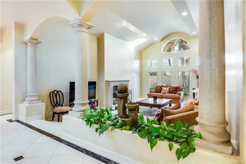 Living room with couch, chairs, columns, and water feature.