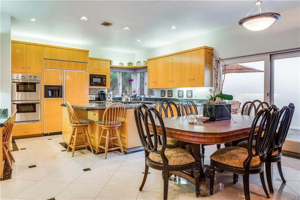 Kitchen with yellow cabinets, island, seating, and dining table.