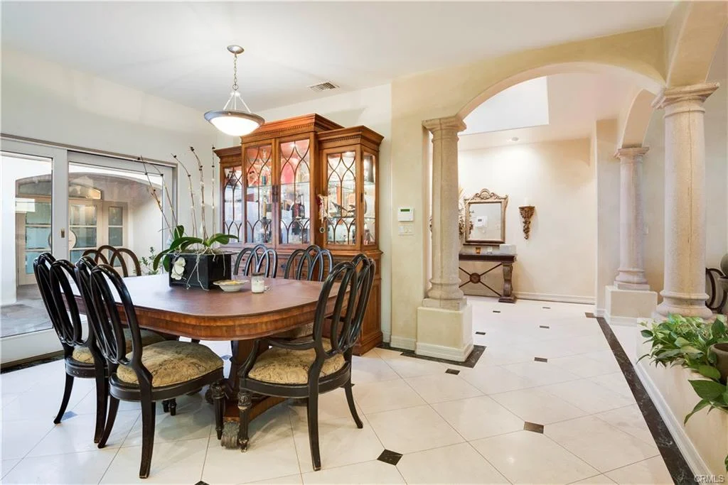 Dining area with wooden table, black chairs, and glass cabinet.