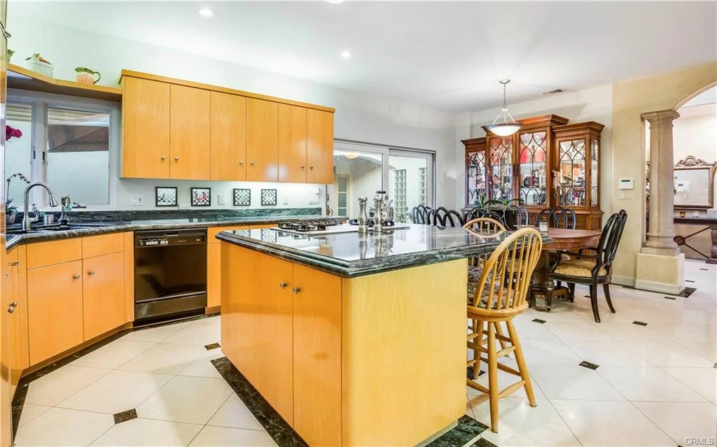Kitchen with orange cabinets, black granite island, and dining table with chairs.