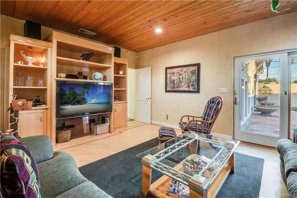 Living room with wooden ceilings, entertainment unit, seating, and coffee table.