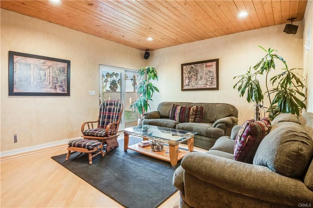 Living room with sofas, armchair, coffee table, and plants.
